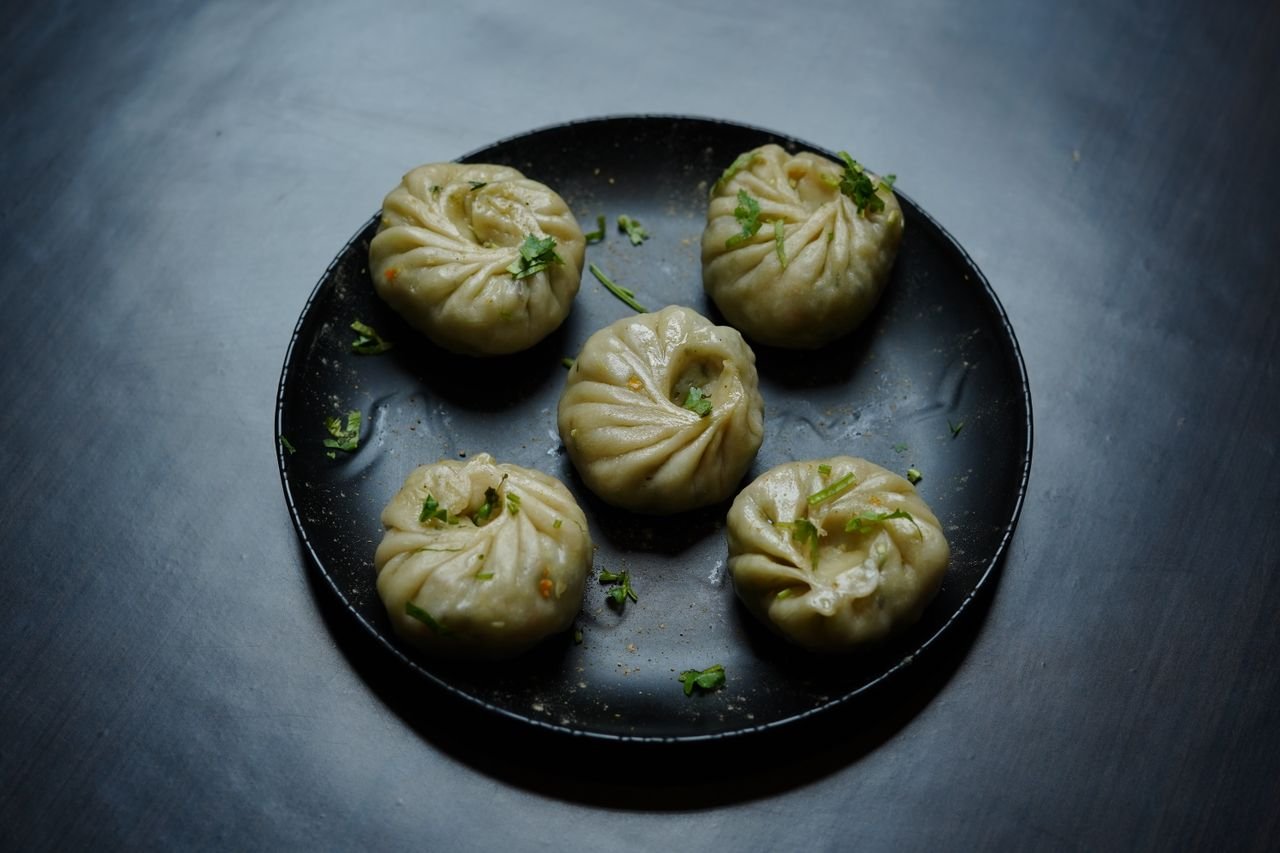 about-01 Plate of Tibetan dumplings (momos) garnished with herbs, perfect for food photography.