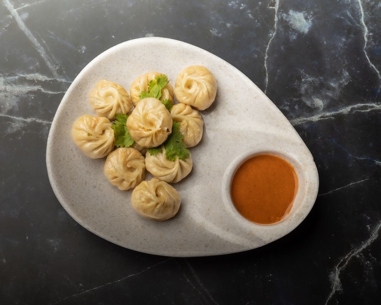 hero-img-01 A plate of traditional Nepalese momos with spicy chutney. Perfect for food enthusiasts seeking authentic flavors.