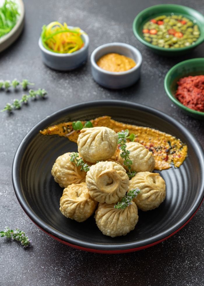services-02 A bowl of fried dumplings served with garnishes and assorted dips, showcasing traditional cuisine.